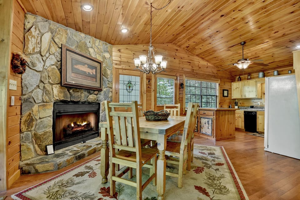 Rustic-style dining area with a stone fireplace and full kitchen.