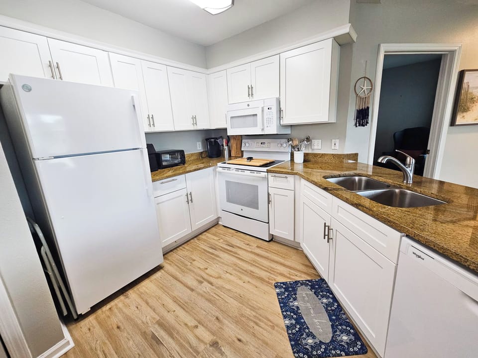 The well-equipped kitchen features white cabinets and white appliances, creating a bright and fresh space to prepare delicious meals for your loved ones.