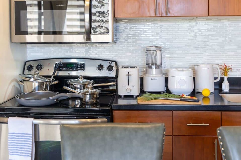 Whip up delicious meals in this fully equipped kitchen, featuring modern stainless steel appliances including a Frigidaire microwave, GE electric range, and essential Cuisinart small appliances