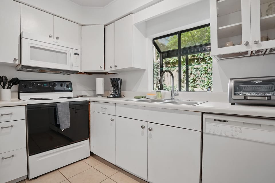 Efficient Kitchen with Full-Size Fridge - White cabinetry, drip coffee maker, and full-size appliances keep the kitchen practical.