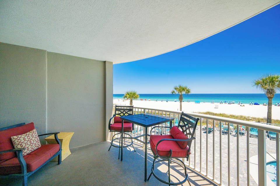 Relax on the balcony with cozy seating and enjoy the impressive view of the beach and pool area below