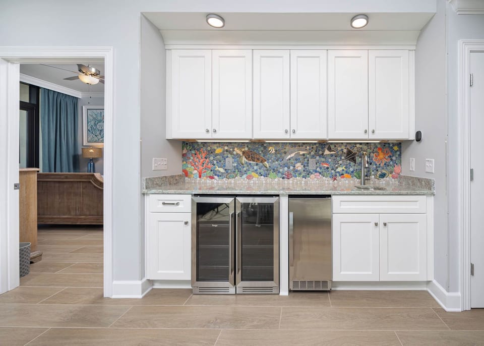 Discover a vibrant kitchen wet bar area with a colorful backsplash, sleek counters, and wine cooler