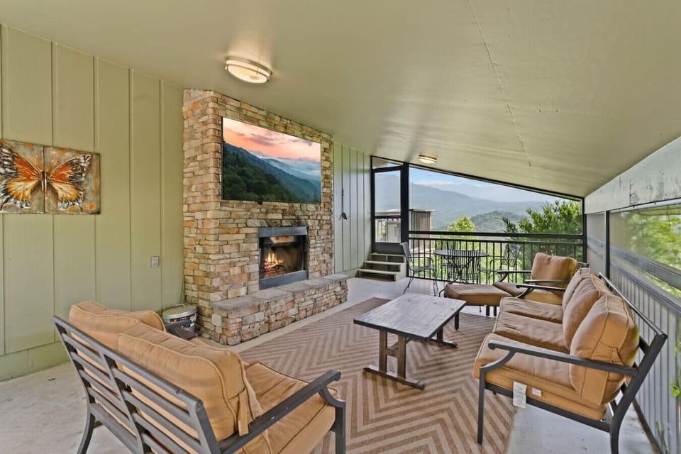 Enjoy mountain breezes on this covered patio complete with a cozy fireplace, Large TV, cushioned seating, and scenic views.