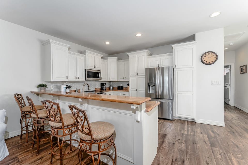 Fully equipped kitchen with stainless steel appliances, granite counters, and bar seating for casual dining.
