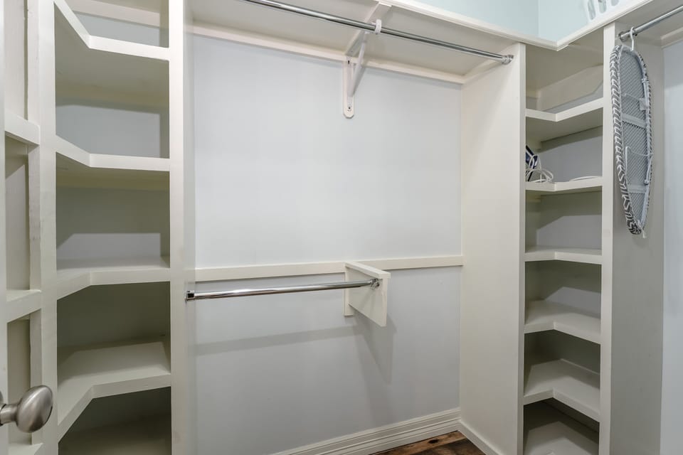 Spacious walk-in closet with built-in shelving and ample hanging space, perfect for extended stays.