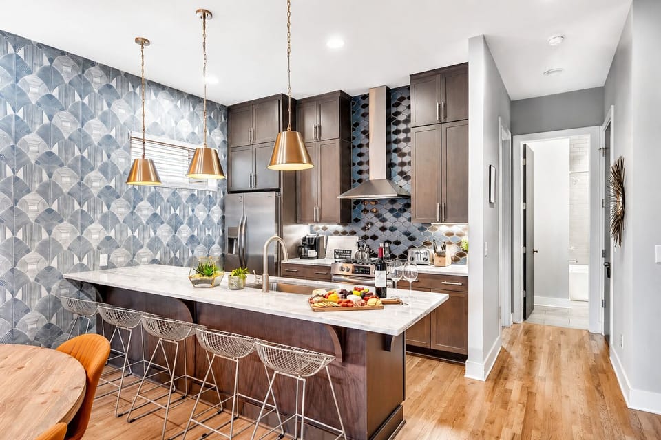 Modern kitchen with a dark island, marble counters, and stainless steel: open to the living room so someone's always cooking and nobody's left out of the conversation