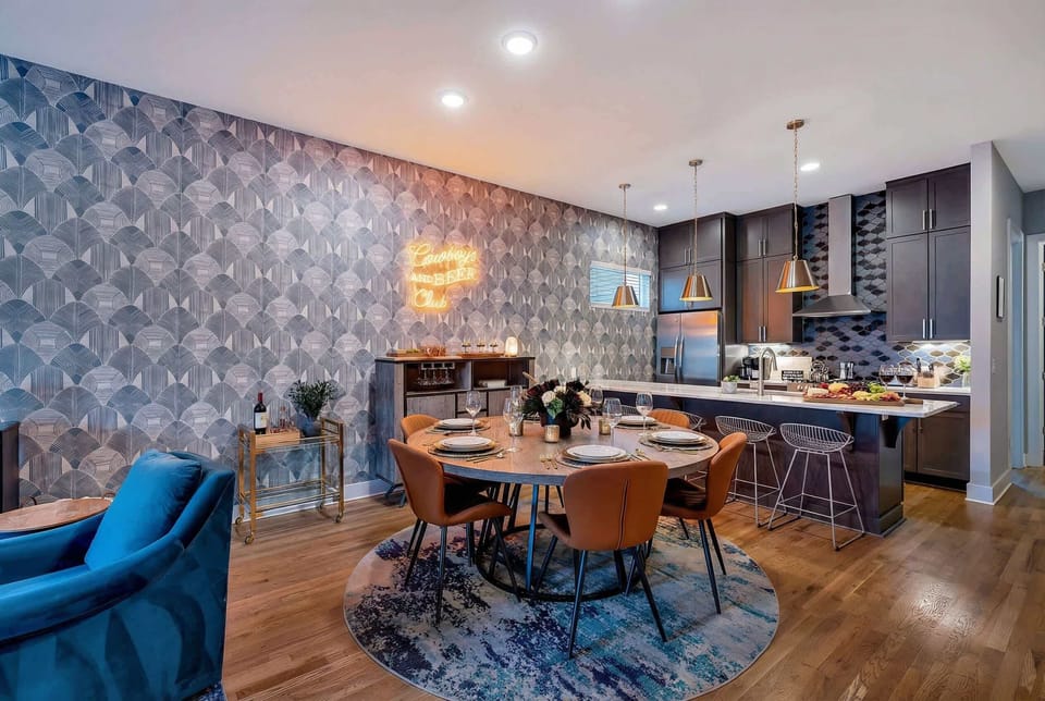 Open-concept dining and kitchen flow into one another, so the cook stays connected to the group, neon sign above the bar sets a fun, casual tone