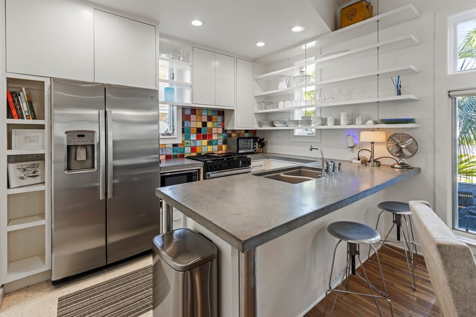 Your modern kitchen gleams with stainless steel appliances, sleek white cabinets, and a vibrant mosaic backsplash that adds personality to your culinary space.