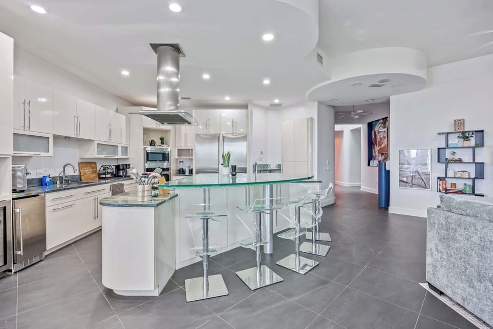 Modern kitchen with a curved glass island and transparent bar stools