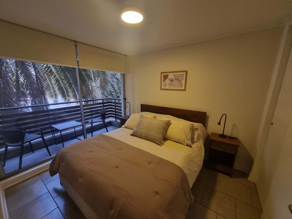 Relax in this cozy bedroom with a private balcony overlooking lush greenery, perfect for a peaceful retreat in the heart of the city.