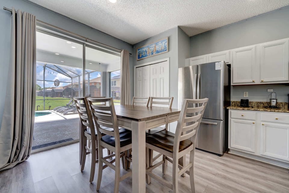 Bright dining area w/ large windows & stainless steel fridge.
