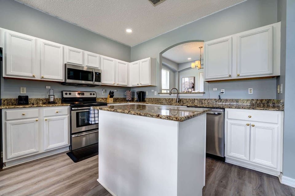 Bright kitchen w/ white island & open sightlines to the dining area.
