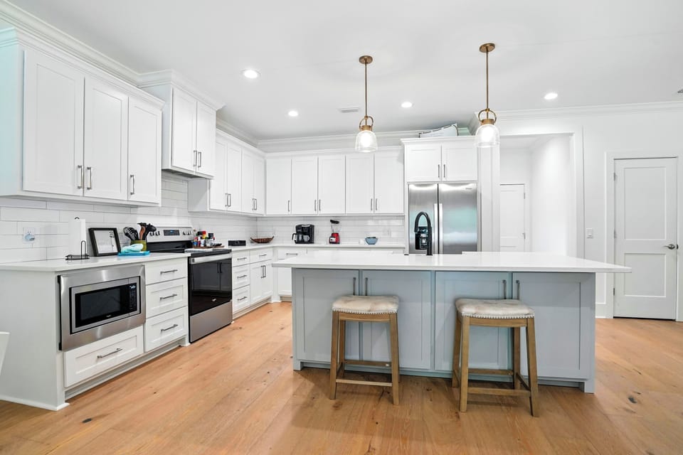 Bright Kitchen with Large Island - Full-size appliances, white cabinetry, and bar seating make meals easy at the center of the home.