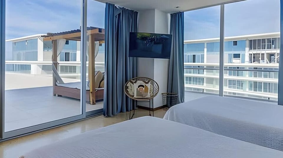 Bedroom corner w/ wraparound windows overlooking nearby buildings