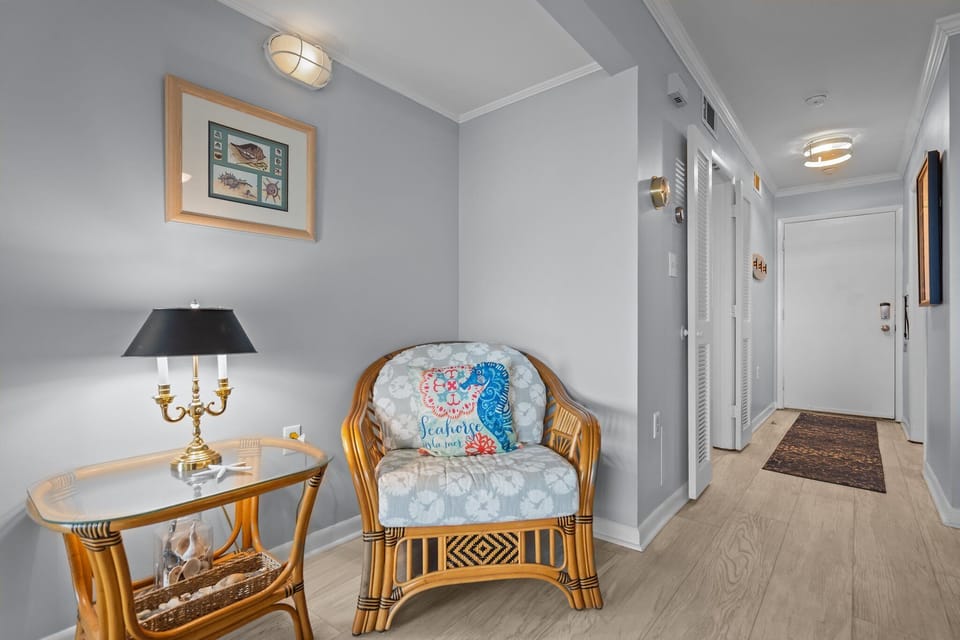 Oak Island, NC living room with gray sofas, wall TV, ceiling fan, sliding doors, ocean-view deck, coastal décor, and bright beach house style.