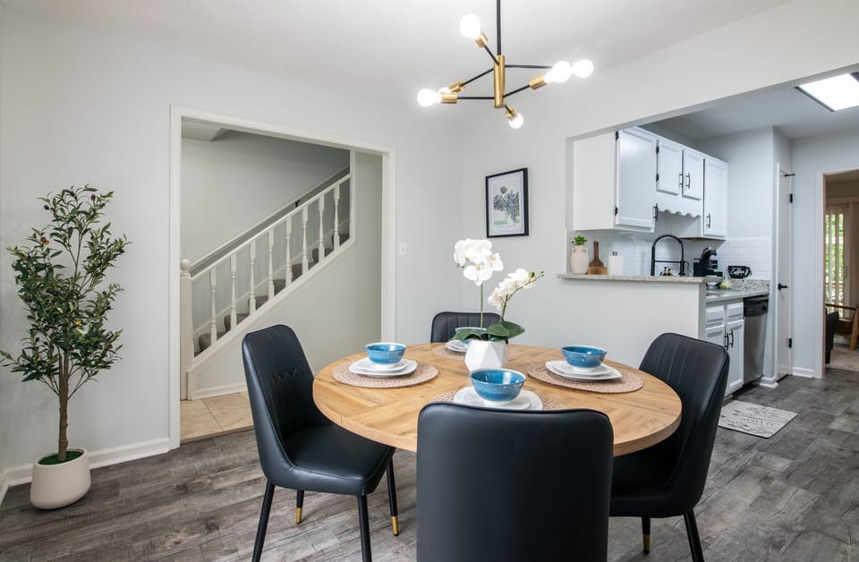 Spacious open-plan layout showcasing the dining and kitchen area, enhanced by a modern chandelier and indoor greenery.