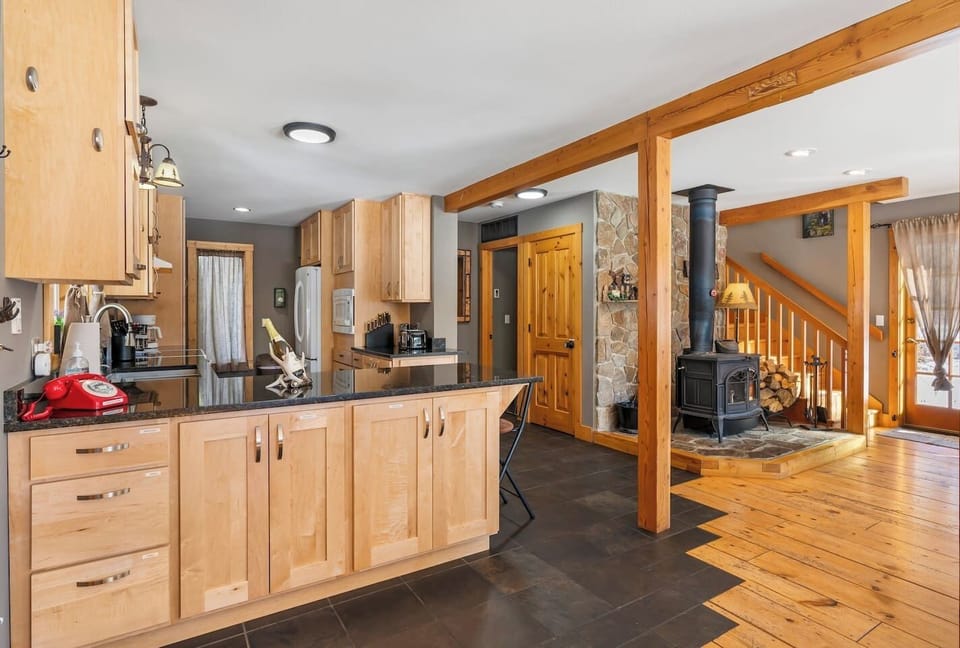 Open concept living space looking from the dining area into the kitchen, hallway to 2nd bathroom, laundry area and wood burning fireplace.