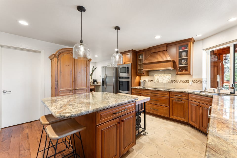 This cozy kitchen features sleek countertops, state-of-the-art appliances, and an island perfect for meal prep or casual dining, with seating for four. Whether you're cooking breakfast or pouring a glass of wine, it’s the heart of the Highland A-frame.