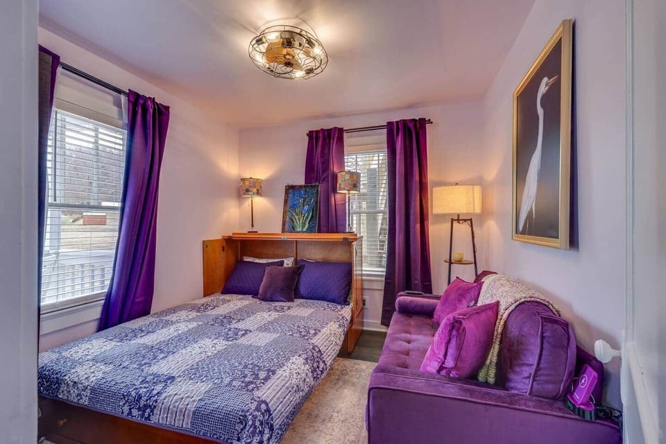 This small bedroom features a full-size bed, smart TV, and a velvet settee.