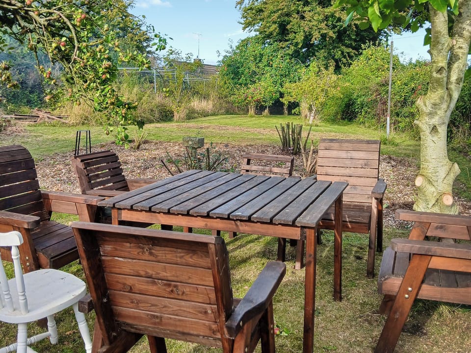 Garden seating area under the walnut tree, with fruit trees at the bottom of the garden | Brockhill House, Beaminster