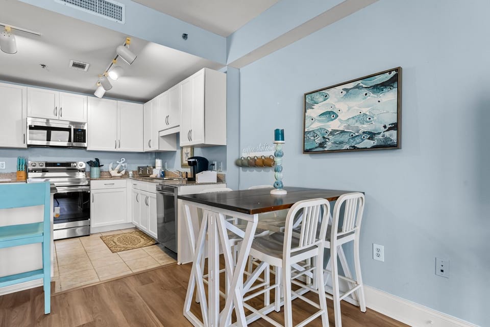 Modern kitchen and dining area with stainless steel appliances and coastal decor.