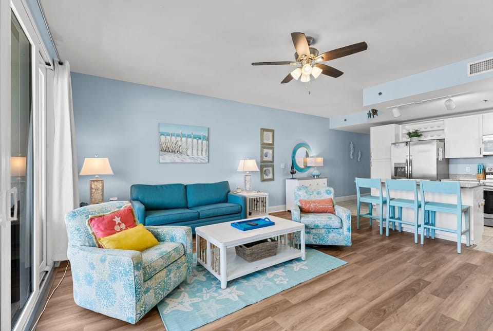 Coastal-themed living area with comfortable seating and an open kitchen.