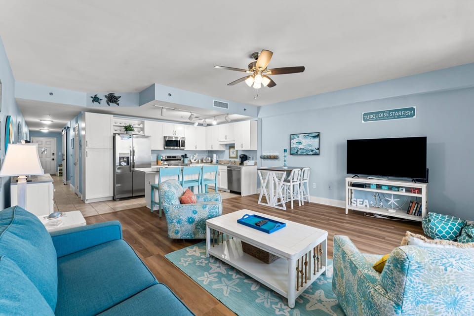 Open-concept living area with coastal-inspired decor and a fully equipped kitchen.