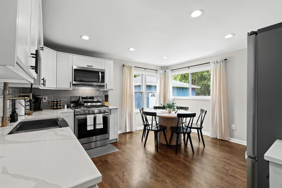 Modern kitchen and dining nook with stainless steel appliances, sleek countertops, and a sunlit corner perfect for morning coffee or casual meals.