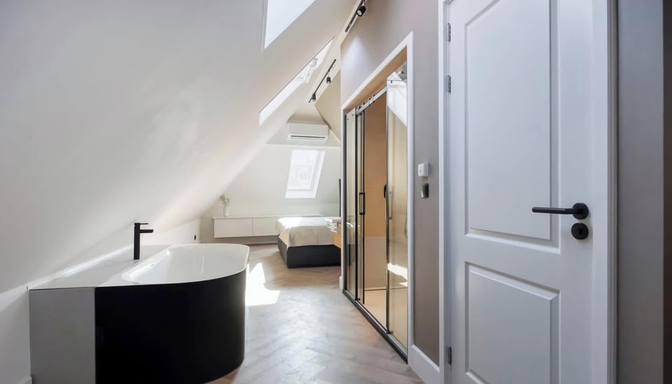 Freestanding tub under a skylight, tucked into the roofline — a private, spa-like escape.