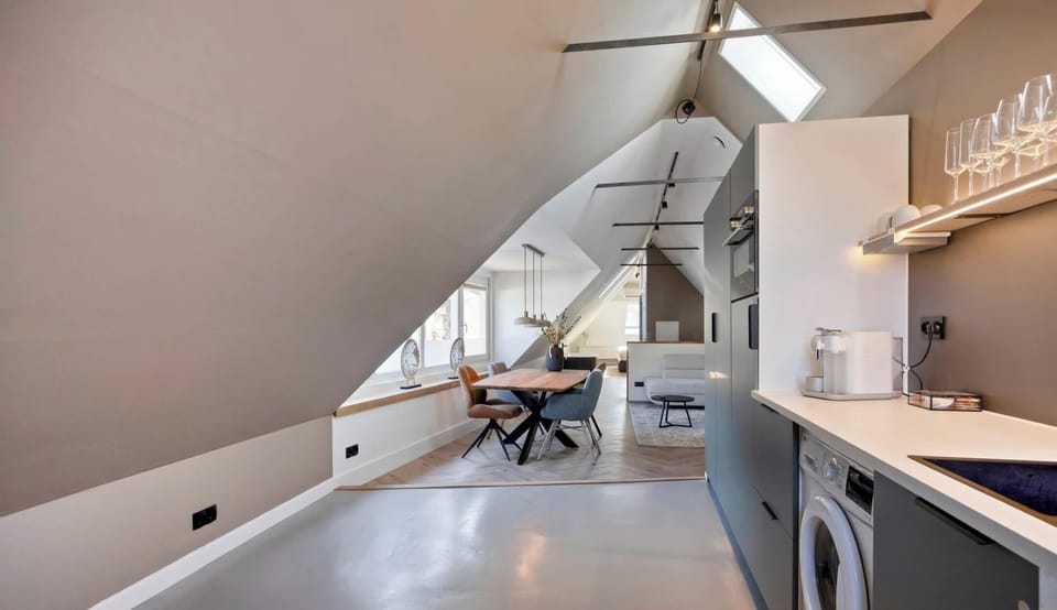 Open-concept layout combining a clean cooking space with relaxed seating under vaulted ceilings.