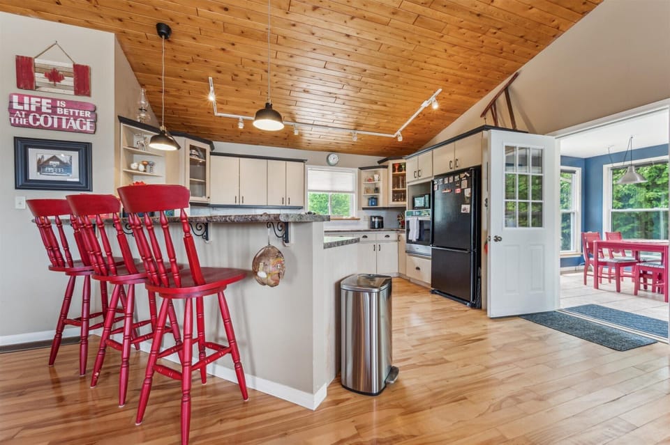 Fully equipped kitchen and bar seating under vaulted wood ceilings—ideal for group meals and morning coffee.