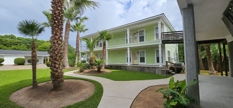 Charming coastal home with double porches and a lush palm-lined courtyard