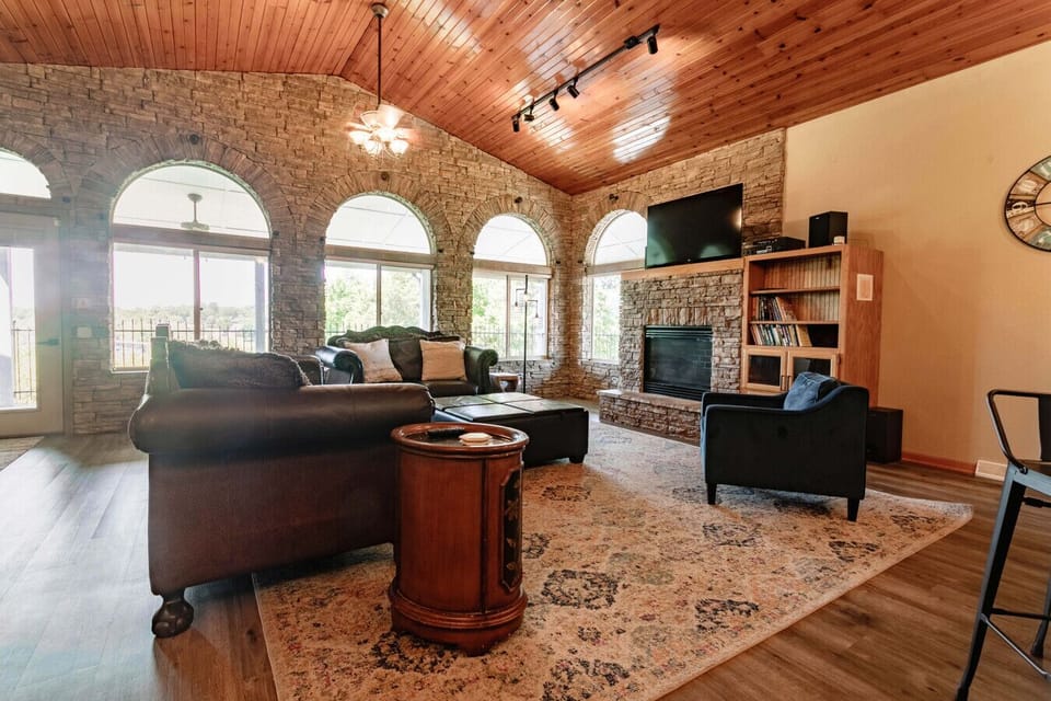 Cozy living room with vaulted ceilings, stone fireplace, and natural light—perfect for relaxing.