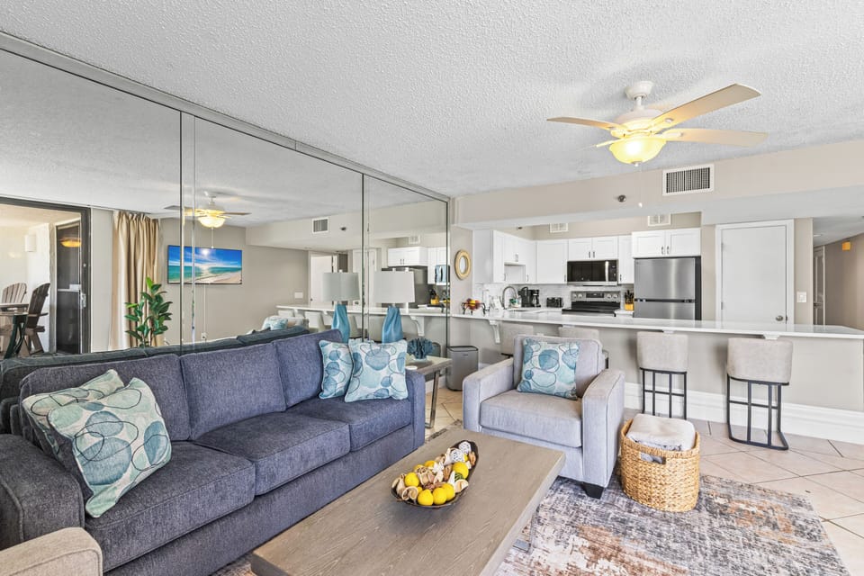 Unwind in your spacious living room with plush seating and ocean artwork, while the fully-equipped kitchen awaits your culinary adventures.