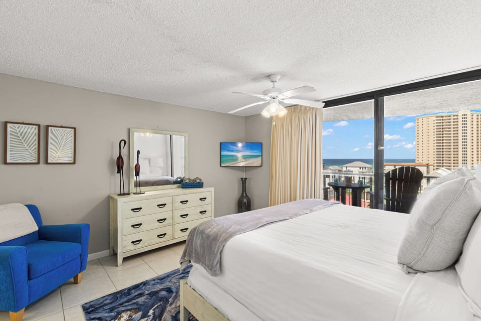 Wake up to stunning ocean views from your private balcony in this bright, coastal-inspired bedroom with comfortable king bed and relaxing blue accents.