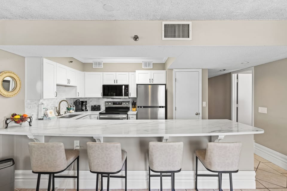 Your modern kitchen features sleek white cabinets, stainless appliances, and a spacious breakfast bar perfect for morning coffee and casual dining.