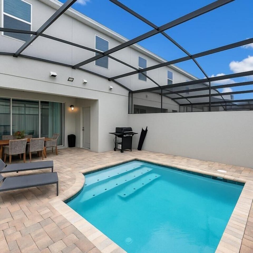 Private pool area with screened enclosure and outdoor dining set.