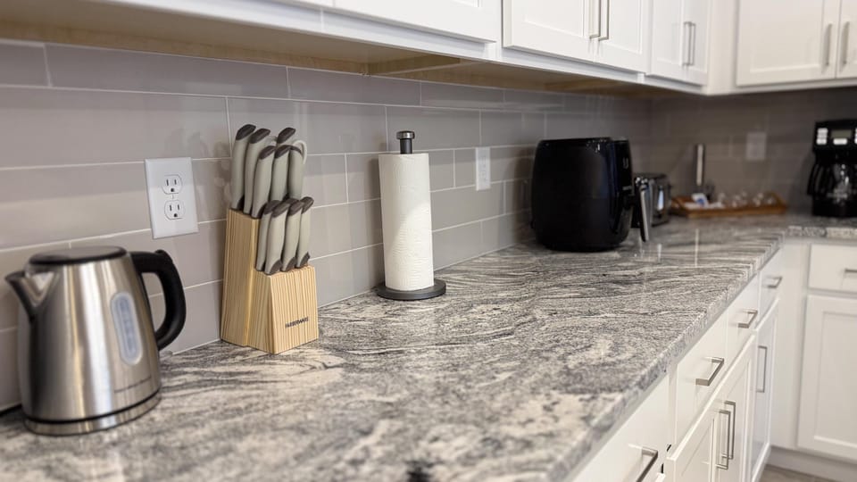 Modern kitchen with stainless steel appliances and marble countertops.