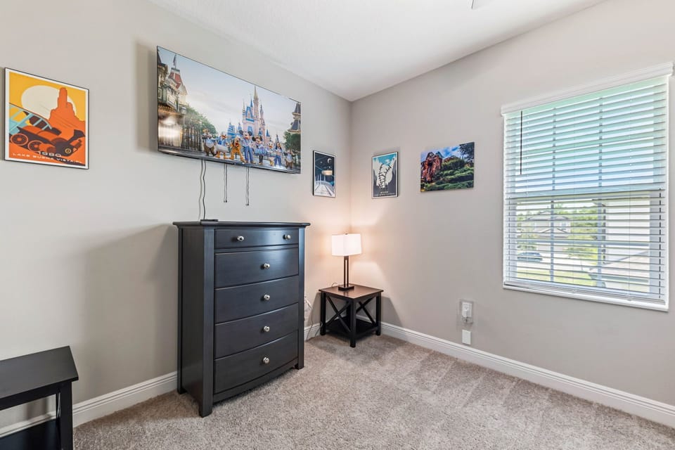 Cozy bedroom with TV, dresser, and bright window view.