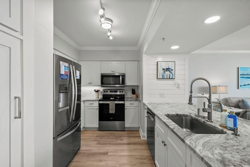 Whip up meals in this fully equipped kitchen featuring stainless steel appliances, beautiful countertops, and coastal charm, perfect for enjoying beachside breakfasts or sunset dinners at your Panama City Beach getaway.