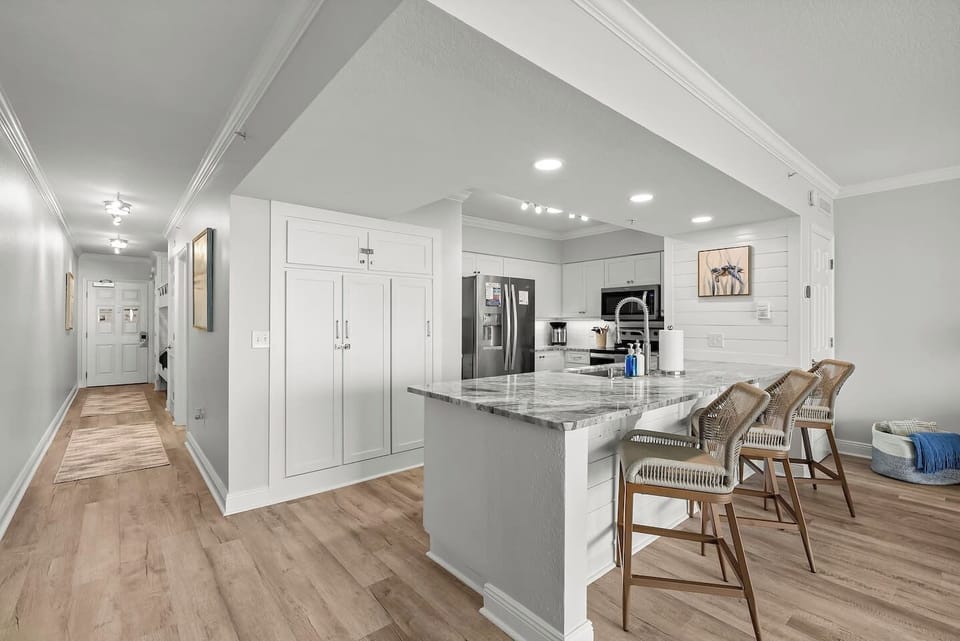 Cook, gather, and unwind in this bright coastal kitchen featuring quartz counters, stainless steel appliances, and bar seating, perfect for meals and conversation after a day at Panama City Beach. 🌊🍽️
