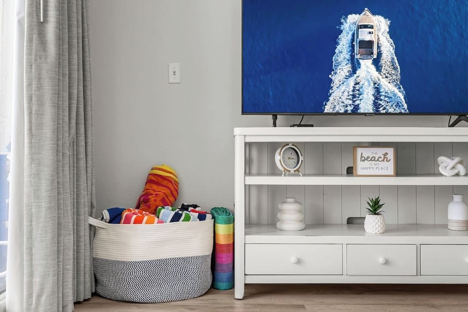Beach vibes await! Enjoy cozy coastal decor, a smart TV for relaxing nights in, and a basket stocked with colorful beach towels ready for your next sun-soaked adventure.