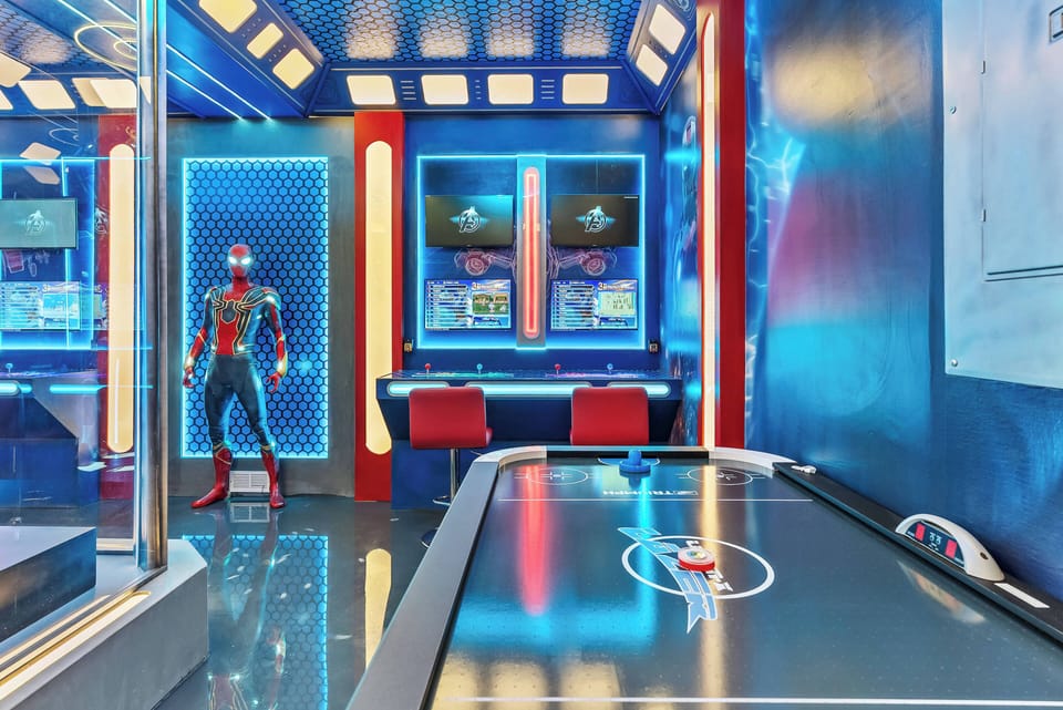 Discover a lively game room with sleek black surfaces and vibrant blue accents, ideal for entertaining evenings. Enjoy neon lights, an exciting air hockey table, and a fun life-sized figure that enhances your experience.