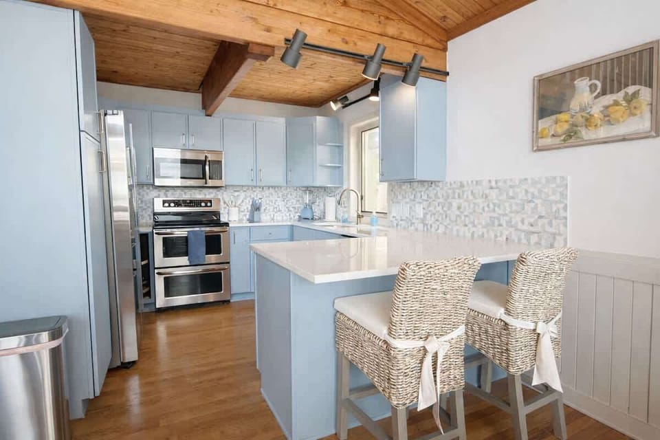A cozy updated and fully stocked kitchen with new appliances, dishes provided for indoors and outdoors, additional seating, and plenty of prep and storage space.