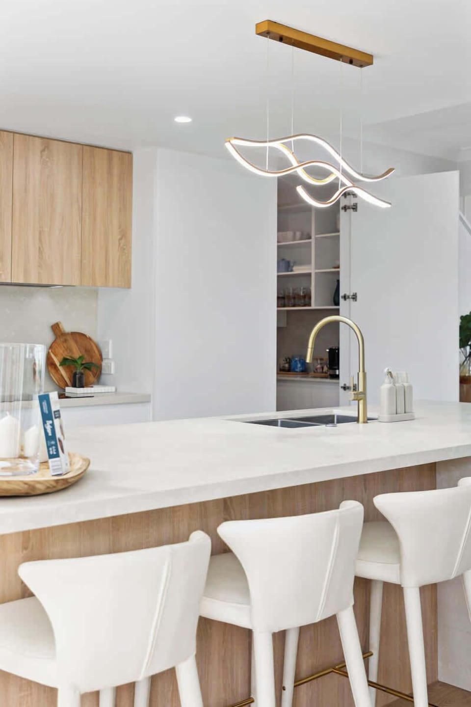 Designer kitchen featuring a large island with bar stools, dishwasher and quality appliances. Light-filled and open-plan, it flows seamlessly to indoor-outdoor dining, making it ideal for entertaining, family meals and relaxed holiday living.