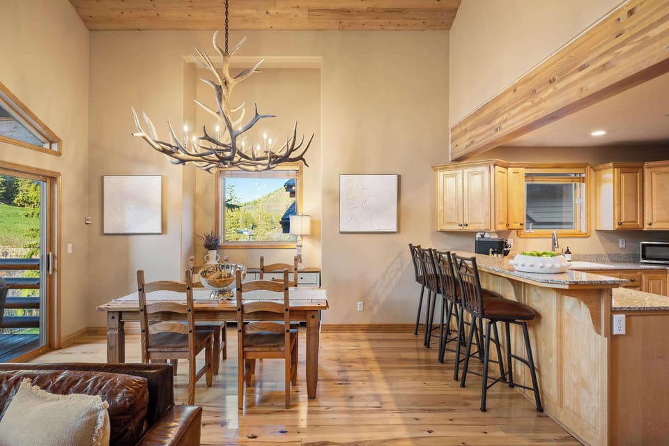 Cozy table for six framed by large windows overlooking mountain scenery.