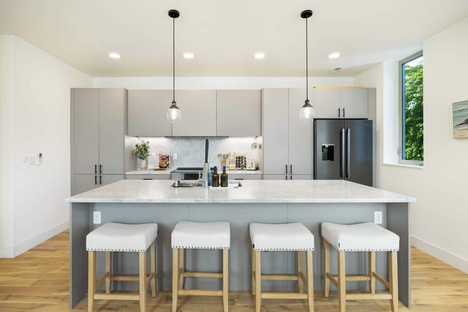 A chef's dream kitchen featuring a massive marble island, matte black fixtures, and integrated high-end appliances.