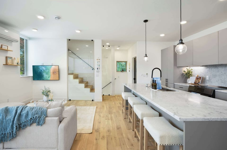 Seamless great room design blending a media lounge with a gourmet kitchen and industrial-chic staircase.