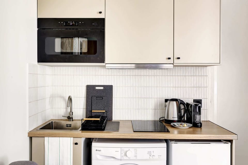 Kitchenette fonctionnelle et équipée : machine à café, micro-ondes, rangements, plaques, etc.