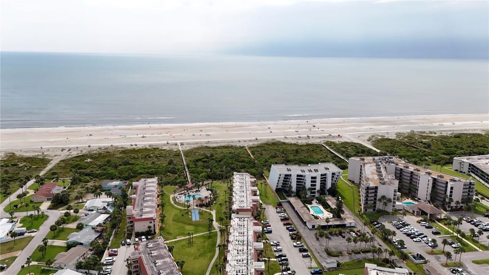 - Aerial view of beachside resort shows direct access paths to sandy shoreline  
- Condo complex includes pools shuffleboard courts and tennis for recreation  
- A prime coastal location combining resort amenities and beachfront living  
